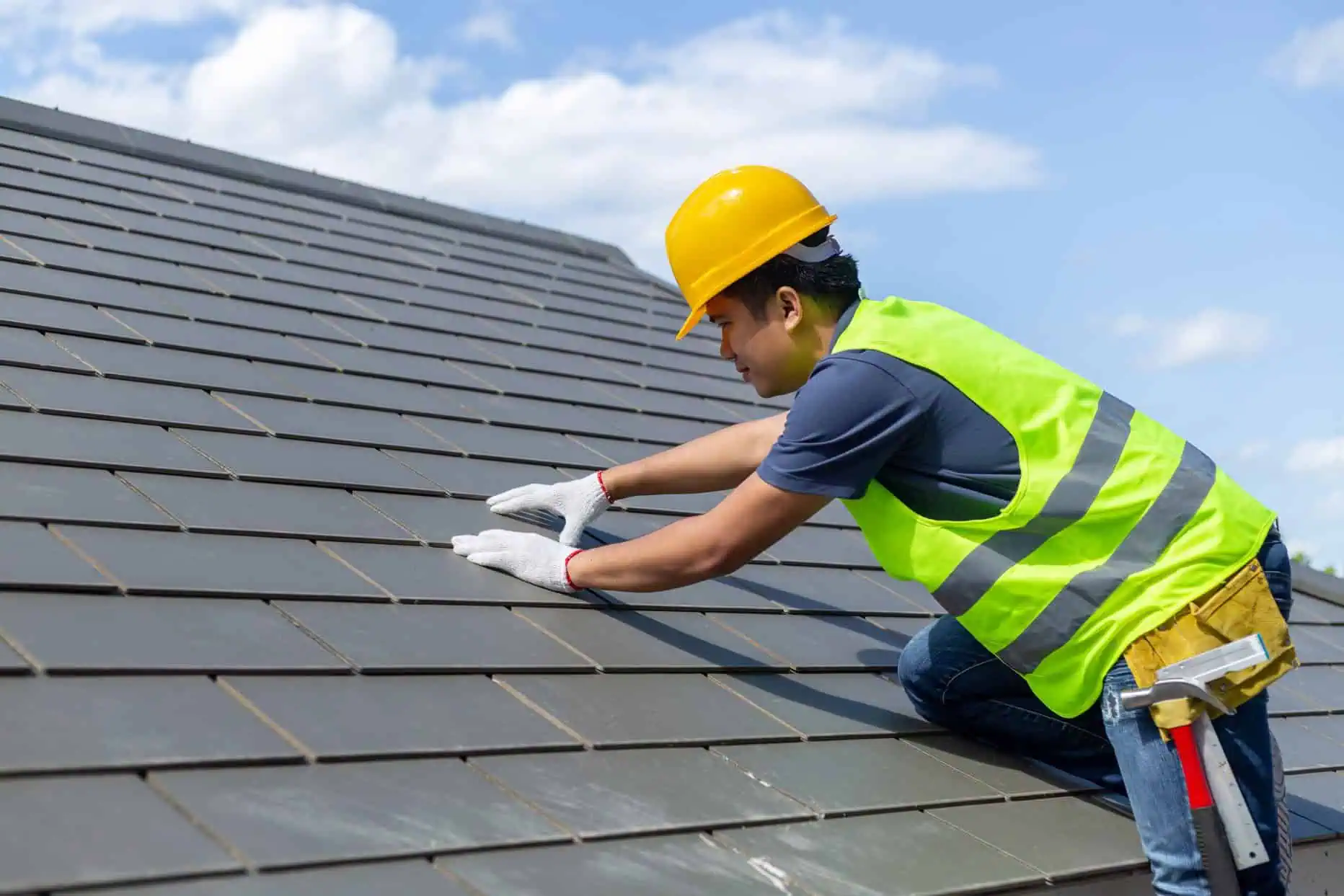 roof-repair-worker-with-white-gloves-replacing-gray-tiles-shingles-house-with-blue-1